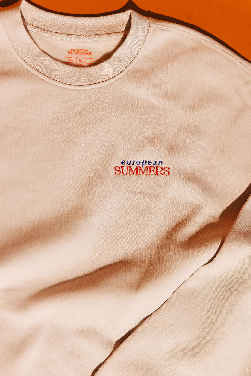 Beige sweatshirt with 'European Summers' text on an orange background