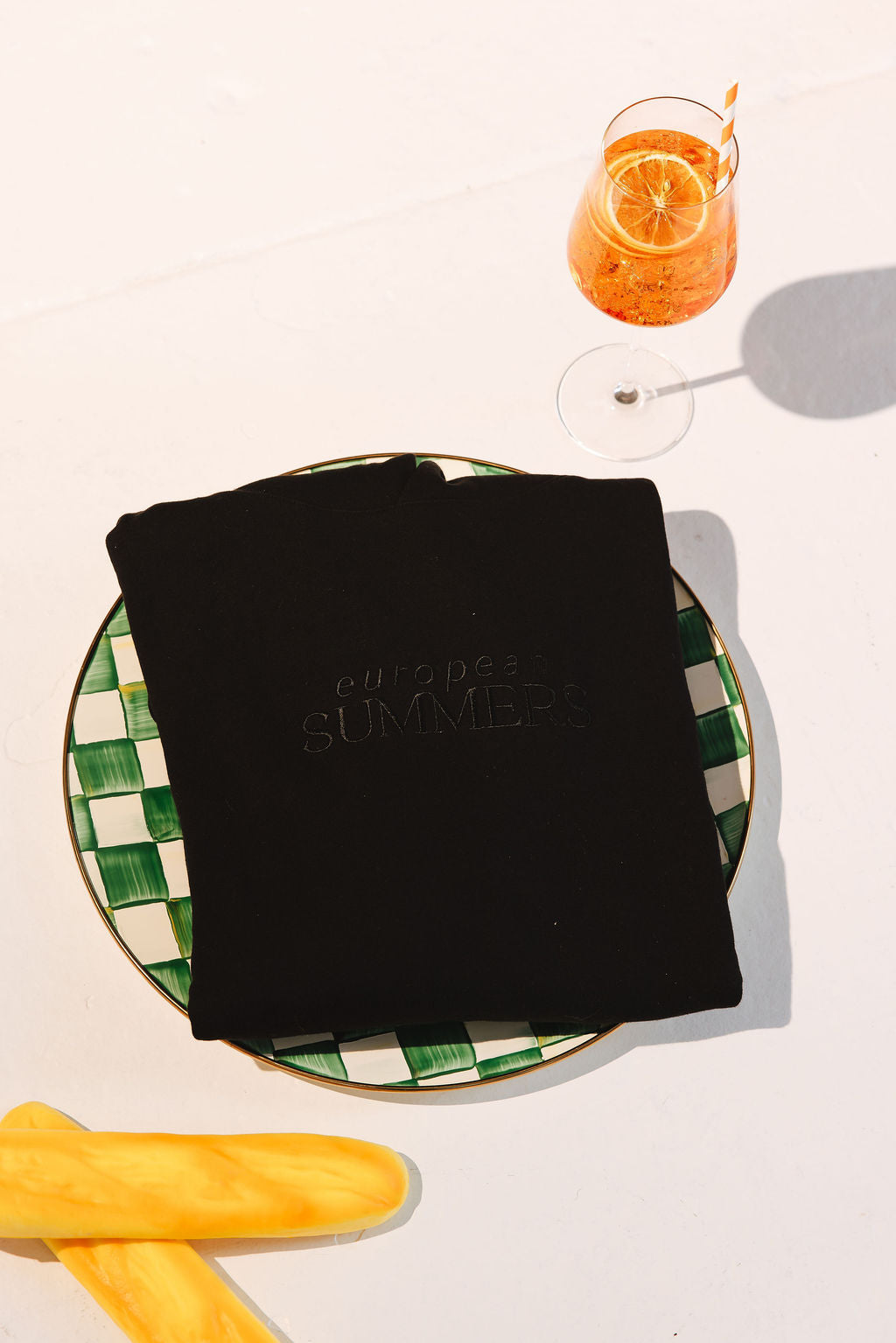 Black t-shirt with 'European Summers' text on a checkered plate with a drink and popsicles.