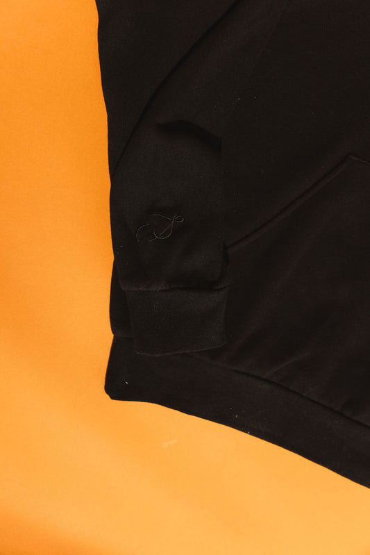 Black fabric with a pocket embroidery detail on an orange background