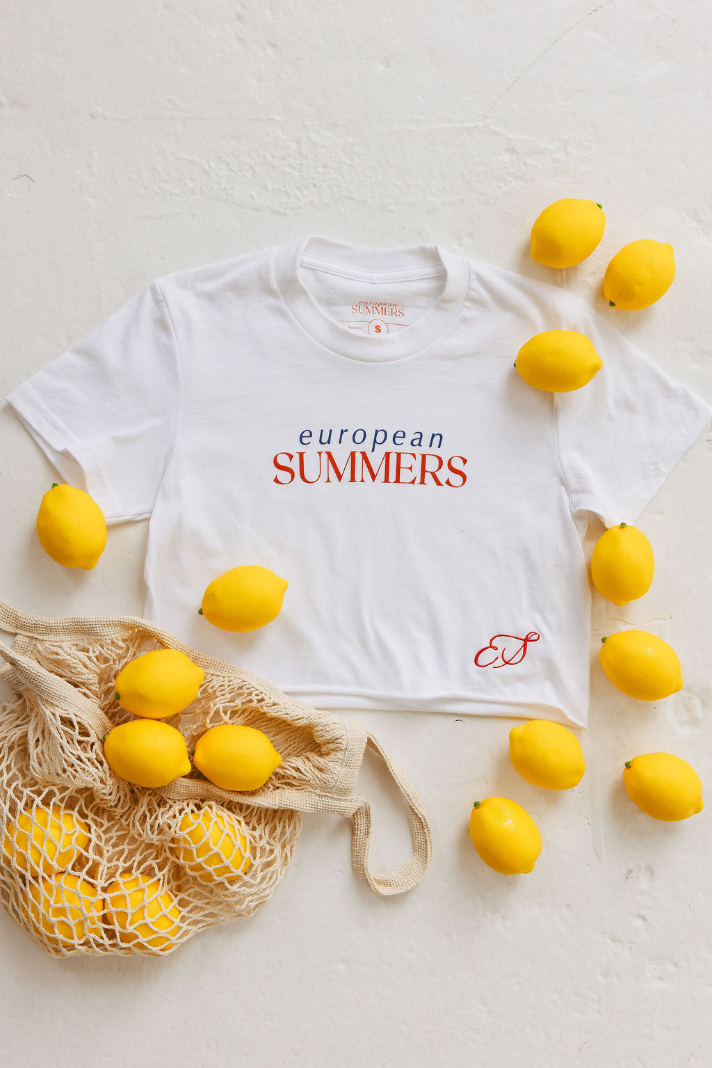 White t-shirt with 'European Summers' text surrounded by lemons on a light surface