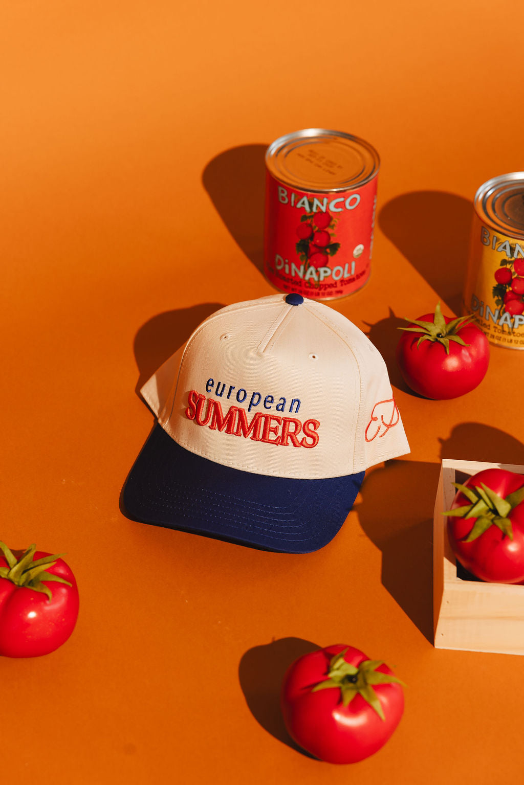 Cap with 'European Summers' text on an orange background with tomatoes and cans.